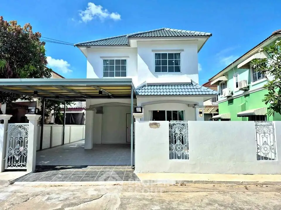 Charming two-story house with gated driveway and tiled roof in a serene neighborhood.