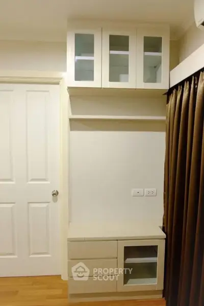 Modern storage unit with glass cabinets and drawers in a stylish room.
