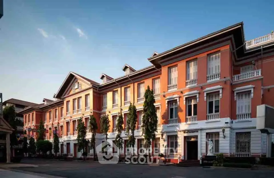 Elegant colonial-style building with lush greenery and spacious layout, perfect for upscale living.