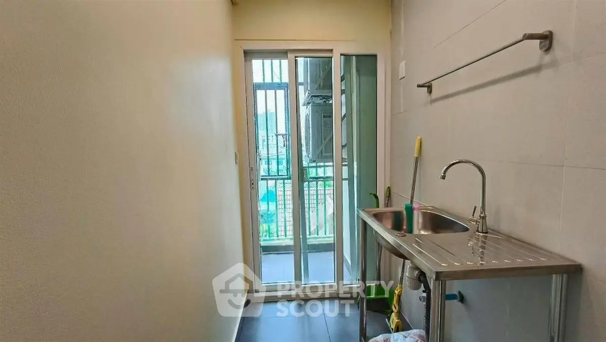 Compact utility area with sink and balcony access in modern apartment.