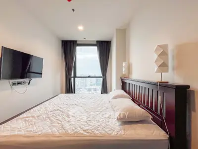 Spacious bedroom with city view, modern decor, and wall-mounted TV.