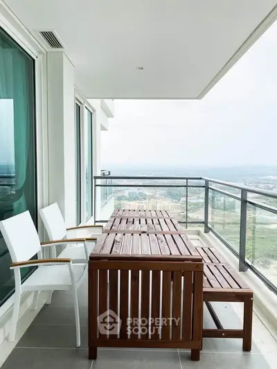 Spacious balcony with wooden furniture and panoramic city view in modern high-rise apartment.