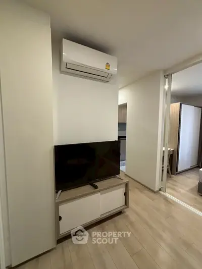 Modern living room with sleek TV setup and air conditioning in a stylish apartment.