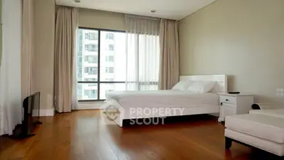 Spacious modern bedroom with large windows and elegant hardwood flooring