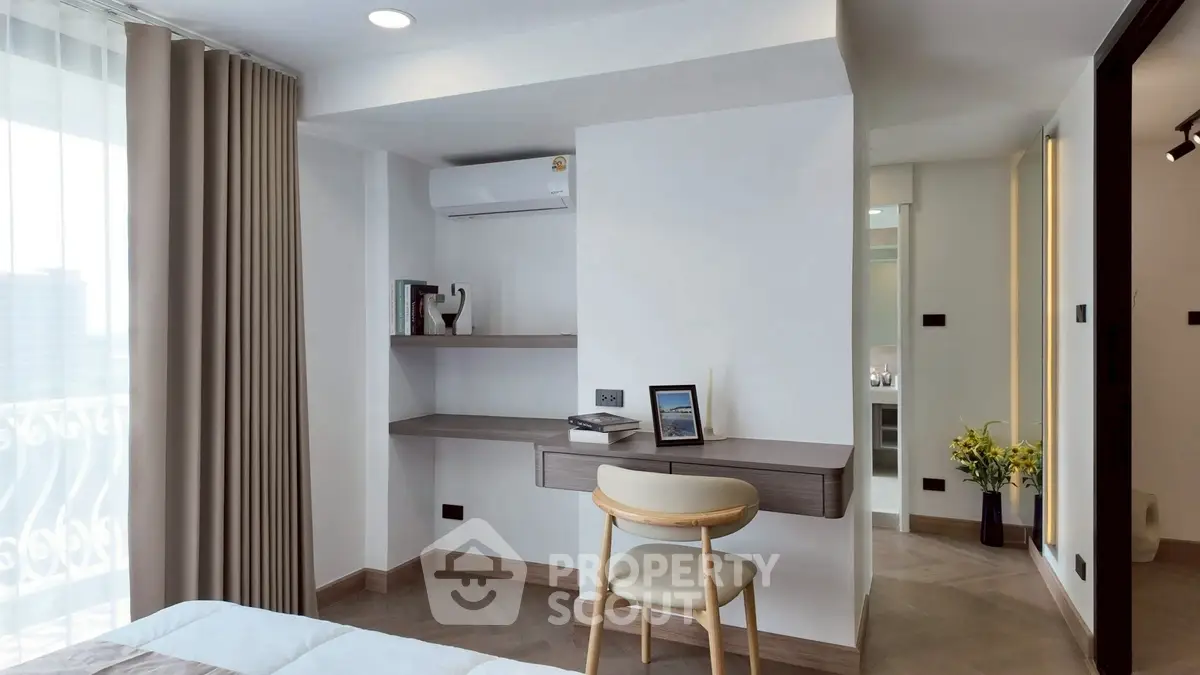 Modern bedroom with built-in desk and air conditioning, featuring elegant decor and natural light.