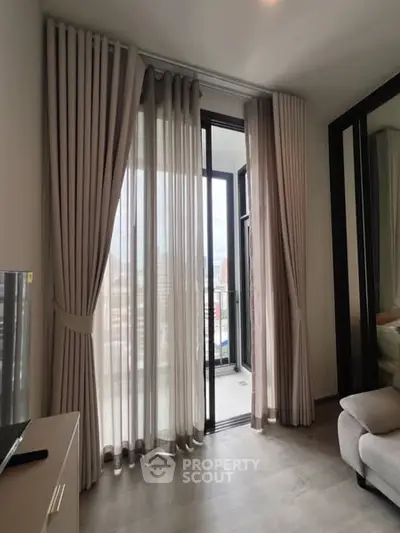 Modern apartment with floor-to-ceiling windows and balcony access, featuring elegant curtains and city views.
