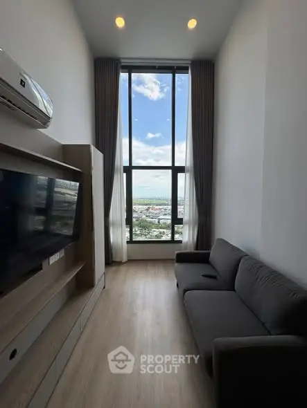 Modern living room with floor-to-ceiling window offering stunning city view.