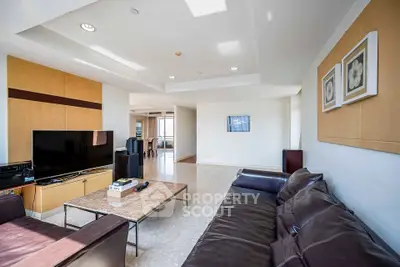 Spacious modern living room with leather sofa and large TV, perfect for relaxation and entertainment.