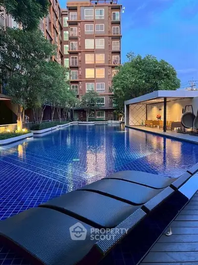 Luxurious apartment complex with stunning pool and modern amenities at sunset.