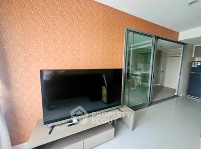 Modern living room with stylish TV setup and sliding glass doors leading to a kitchen area.