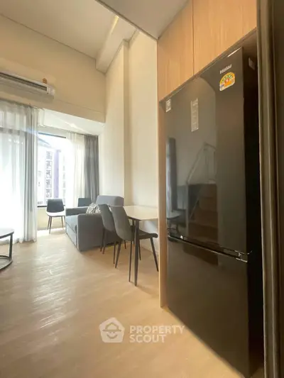 Modern living room with dining area and sleek black refrigerator