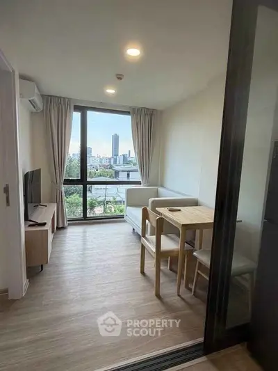 Modern living room with city view, featuring sleek furniture and large windows for natural light.