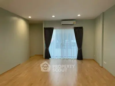 Spacious living room with wooden flooring and large window, perfect for natural light.