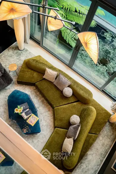 Luxurious living room with unique green sofa and modern lighting, overlooking lush garden view.