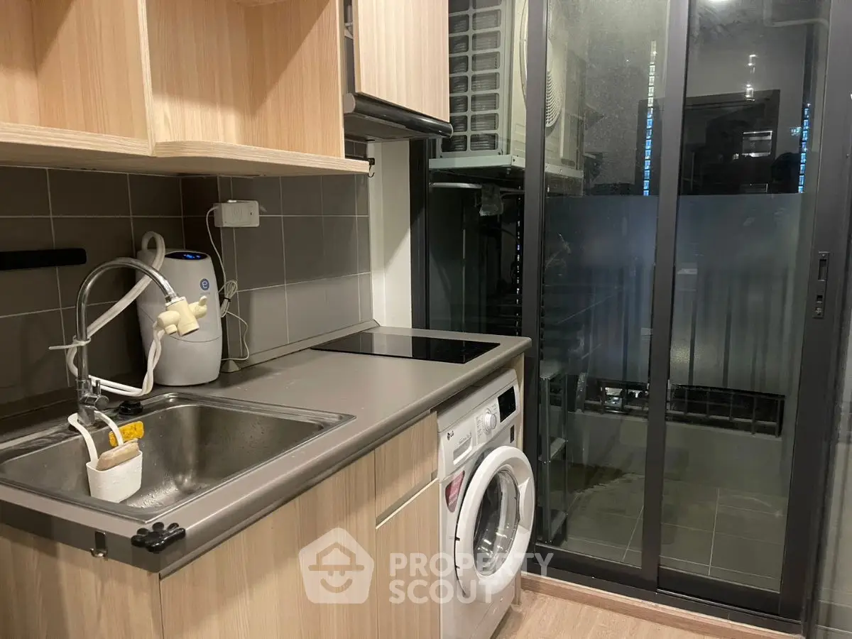 Modern kitchen with washing machine and sleek cabinetry in compact space