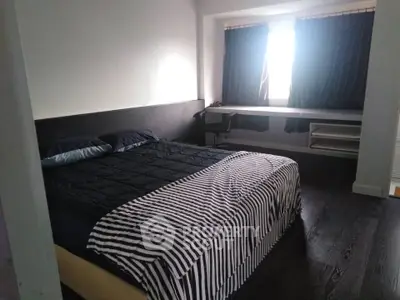 Spacious bedroom with dark wood flooring and large window for natural light.