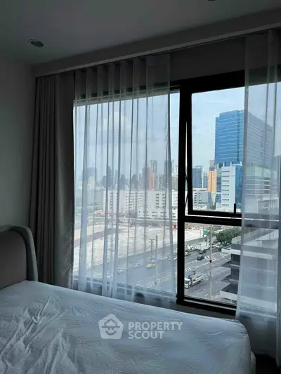 Modern bedroom with large window offering stunning city view in high-rise apartment.
