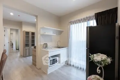 Modern kitchen with sleek design, featuring a microwave, fridge, and elegant cabinetry in a bright, airy space.