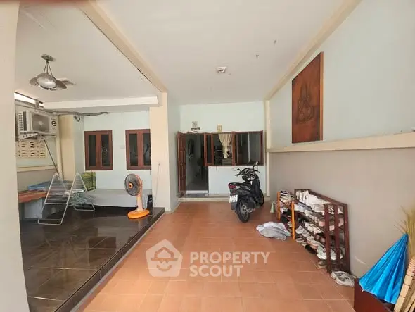 Spacious covered parking area with tiled flooring and storage shelves in a residential property.