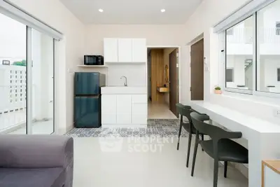 Modern apartment interior with open kitchen and dining area, featuring sleek design and natural light.