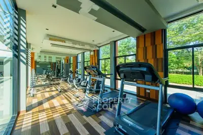 Modern gym with large windows and state-of-the-art equipment in a luxury residential building.
