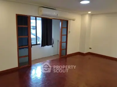 Spacious empty room with wooden flooring and air conditioning, ideal for customization.