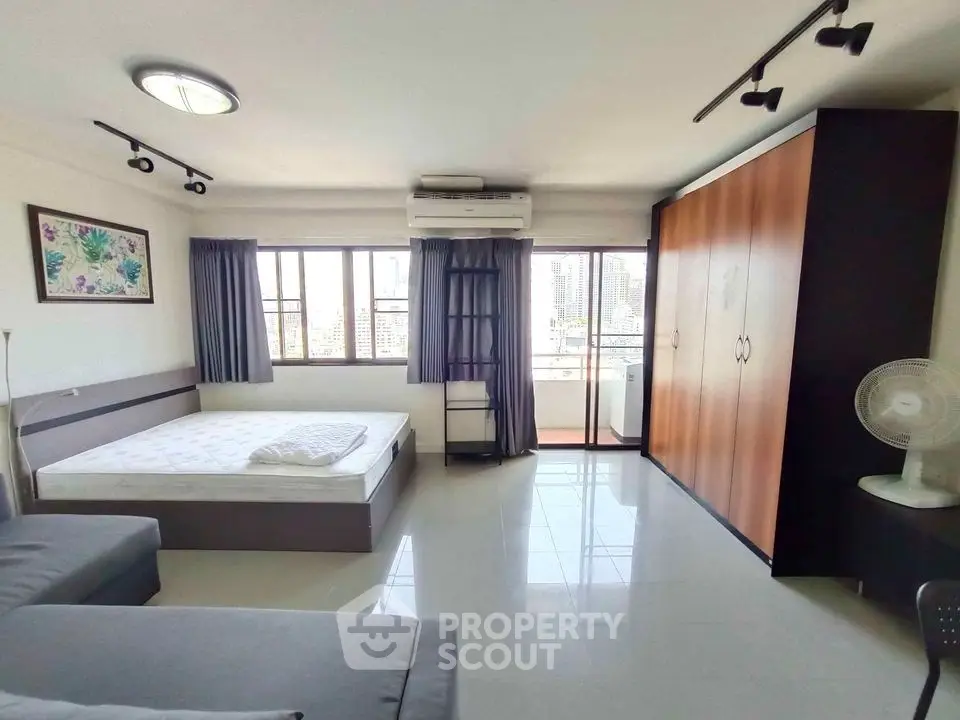 Spacious bedroom with city view, large windows, and modern furnishings in a high-rise apartment.