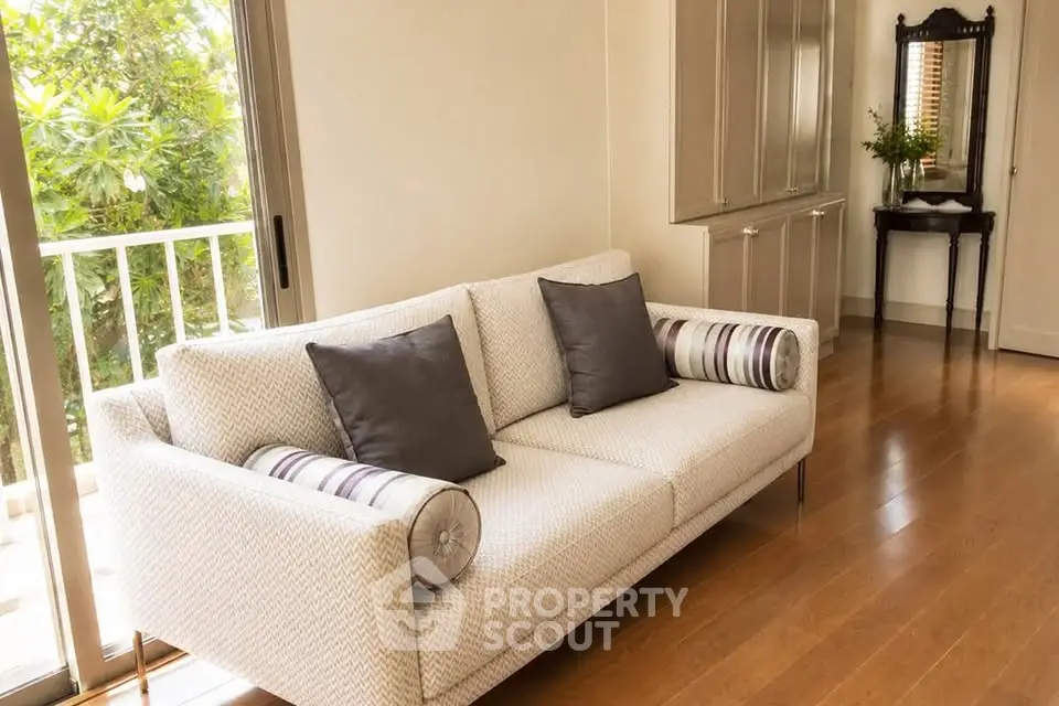 Elegant living room with cozy sofa and natural light from balcony view.