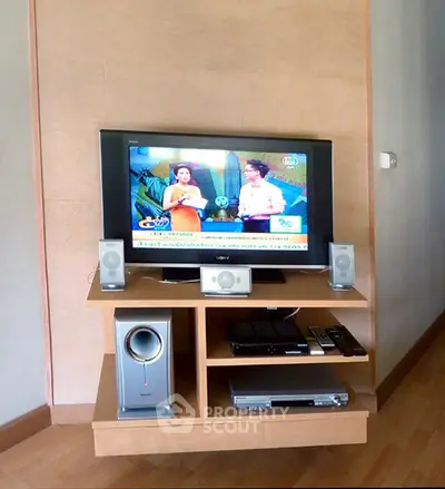 Modern living room with entertainment center featuring TV and speakers.