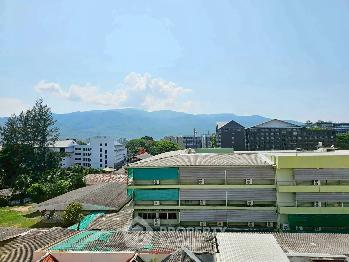 Scenic view of urban buildings with mountain backdrop under clear blue sky.