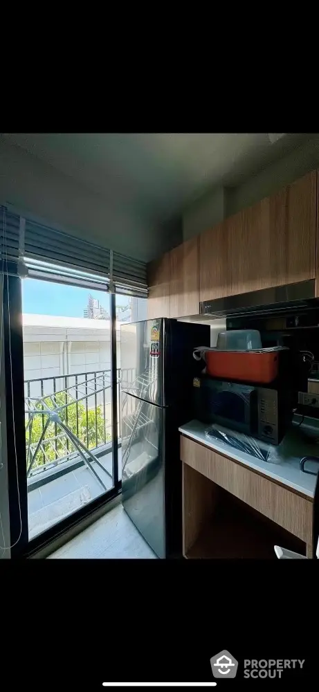 Modern kitchen with balcony view, featuring sleek appliances and ample cabinetry.