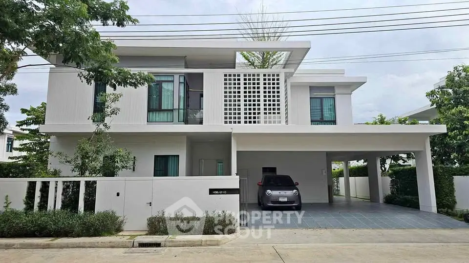 Modern two-story house with carport and lush greenery, showcasing contemporary architecture and spacious design.