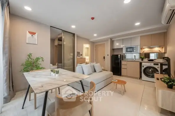 Modern open-plan living room with kitchen, featuring sleek appliances and stylish decor.