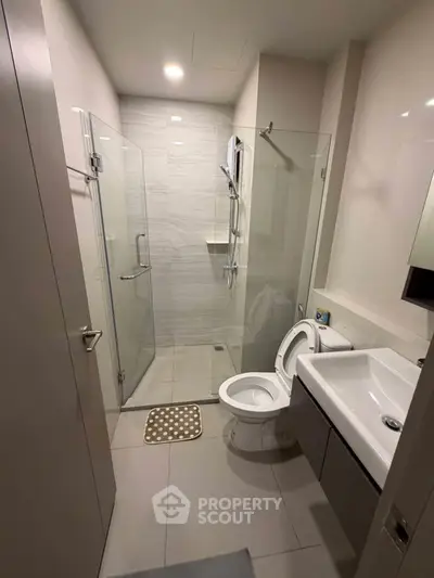 Modern bathroom with glass shower and sleek fixtures in a contemporary apartment.