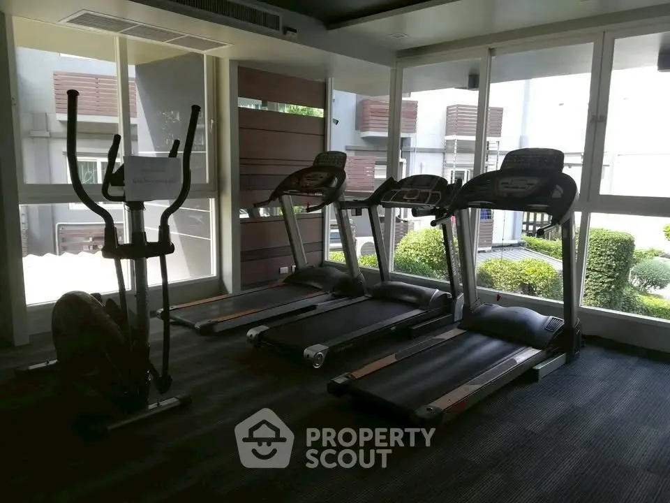 Modern gym with treadmills and exercise bike in a well-lit space with garden view.