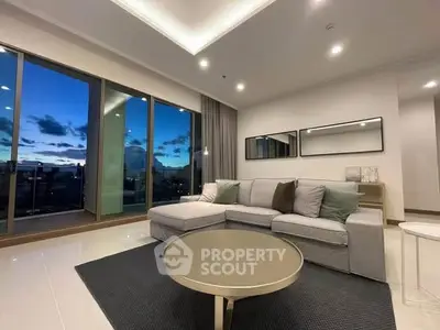Luxurious living room with modern decor and stunning sunset view through large windows.