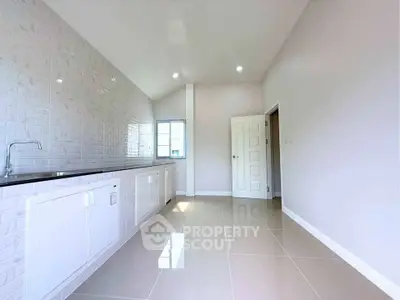 Spacious modern kitchen with sleek white cabinetry and glossy tiled flooring, perfect for culinary enthusiasts.