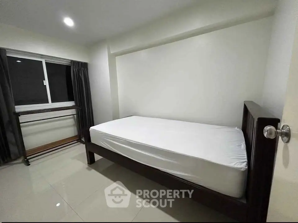 Minimalist bedroom with single bed and window, perfect for cozy living.