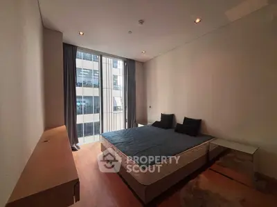 Modern bedroom with large window and stylish decor in a high-rise apartment.