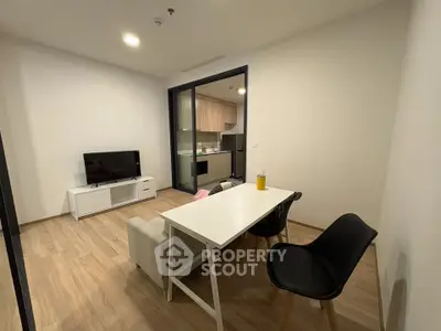 Modern living room with open kitchen, featuring sleek furniture and wooden flooring.
