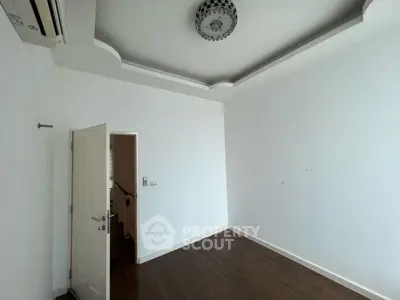 Spacious empty room with elegant ceiling design and wooden flooring, ready for customization.