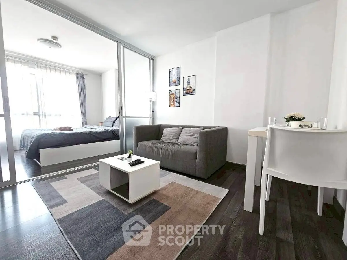 Modern studio apartment with cozy living area and bedroom, featuring sleek furniture and natural light.