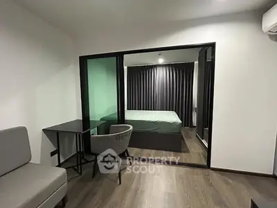 Modern studio apartment with glass partition and sleek furnishings.