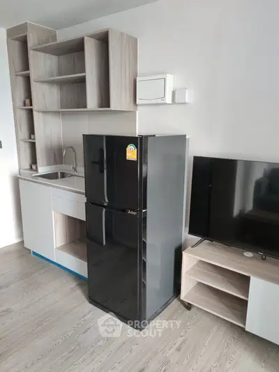 Modern kitchen with sleek black fridge and TV in stylish apartment