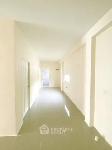 Spacious hallway with glossy tiled flooring and neutral walls in modern home