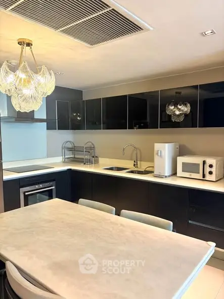Modern kitchen with sleek black cabinets, elegant lighting, and high-end appliances.