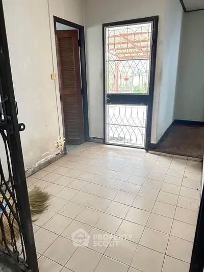 Spacious entryway with tiled floor and secure metal door in a residential property