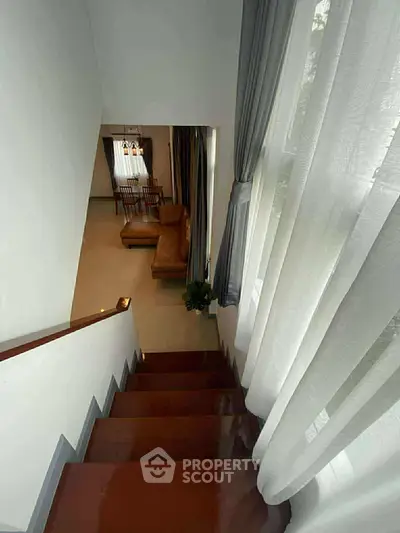 Elegant staircase leading to a cozy living room with stylish furniture and natural light.
