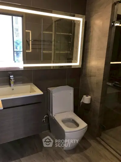 Modern bathroom with sleek fixtures and illuminated mirror in a contemporary apartment.