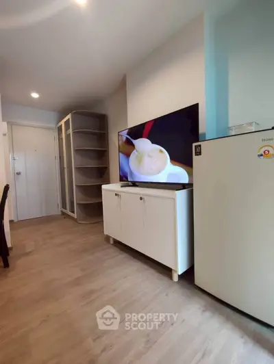 Modern apartment interior with TV, fridge, and stylish storage solutions.